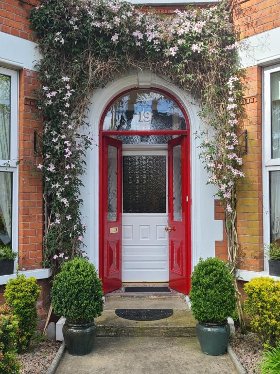 een rode deur op een bakstenen huis met bloemen bij Roseleigh House in Belfast