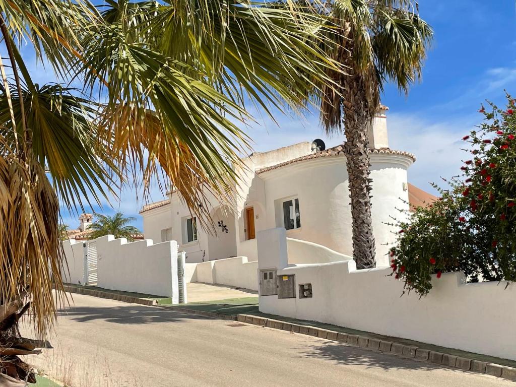 a white house with a palm tree in front of it at Vakantiewoning CasaLucka4enjoy private pool and mountain view regio Calpe-Jalon in Jalón