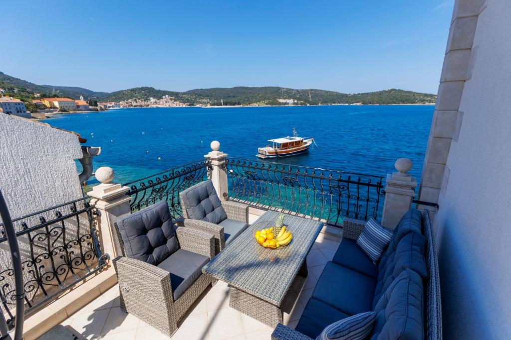 einen Balkon mit einem Tisch und Stühlen sowie einem Boot im Wasser in der Unterkunft Seafront Apartment For4 in Vis