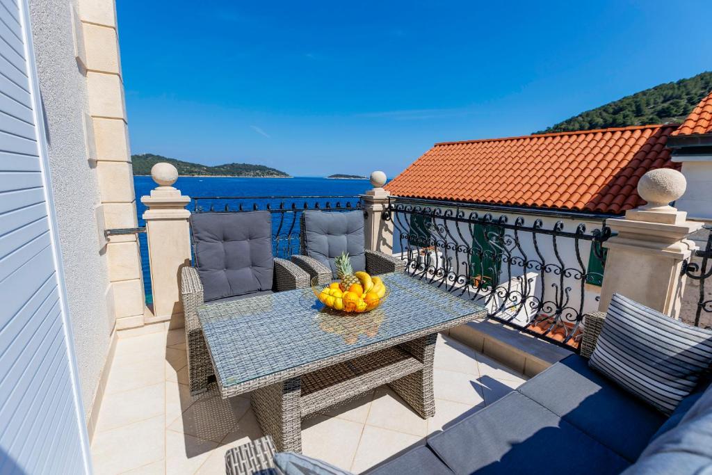 una mesa en un balcón con un bol de fruta en Seafront Apartment Duo en Vis