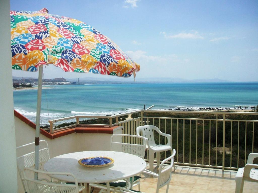 une terrasse avec une table, des chaises et un parasol dans l'établissement Punta Grande - Scala dei Turchi, à Realmonte