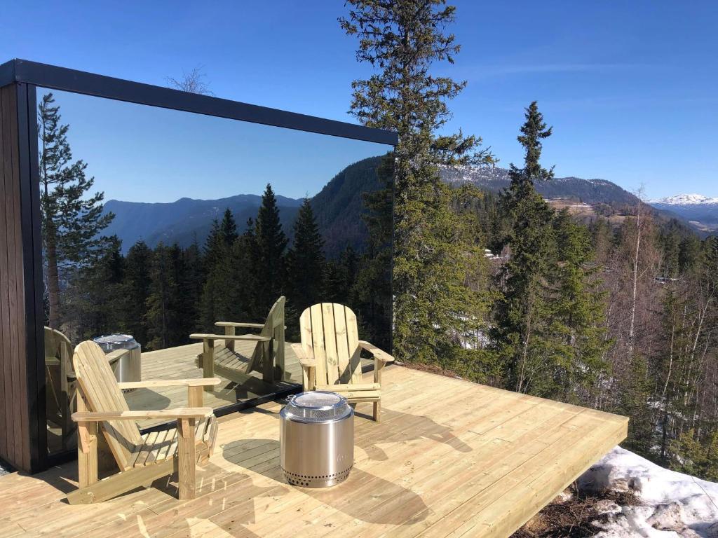 a wooden deck with chairs and a table and a view at Vidsyn Midjås in Vistad