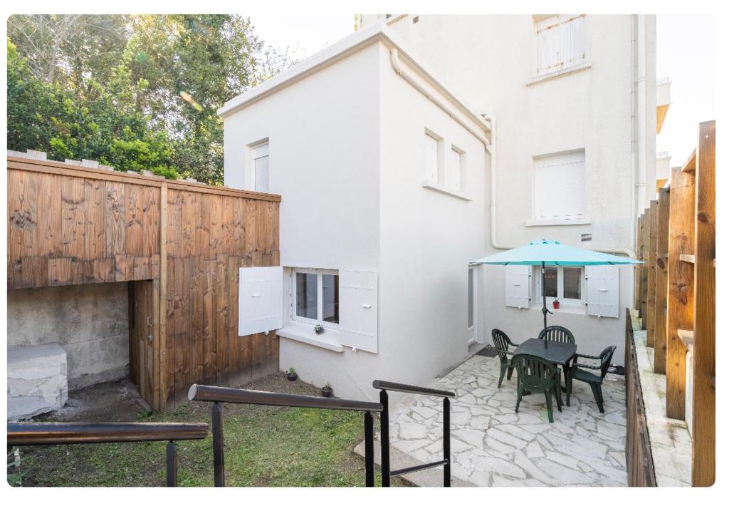 a patio with a table and a blue umbrella at Appartement 200 m plage avec terrasse et jardin in Royan