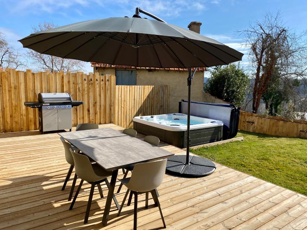 patio ze stołem, parasolem i wanną z hydromasażem w obiekcie Le gîte de La Villénie - en pleine Nature - 5 min centre ville de Sarlat w mieście Sarlat-la-Canéda
