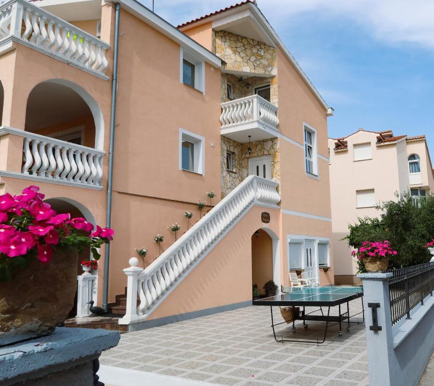 een villa met een balkon en een tafel voor een gebouw bij Apartments Villa Dolmar in Vodice