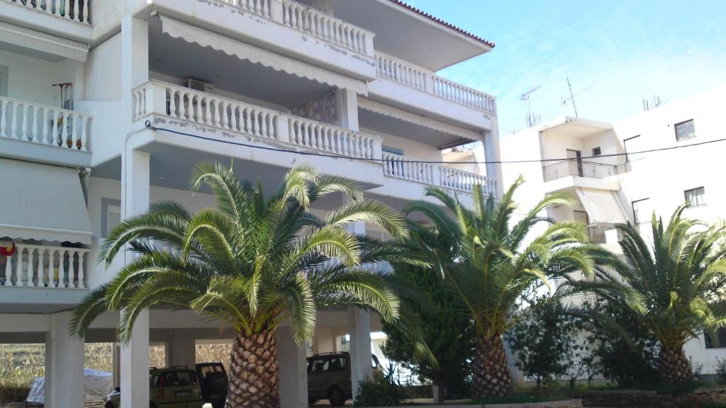 a white building with palm trees in front of it at Anna's Sweet Home Akrata in Paralía Akrátas
