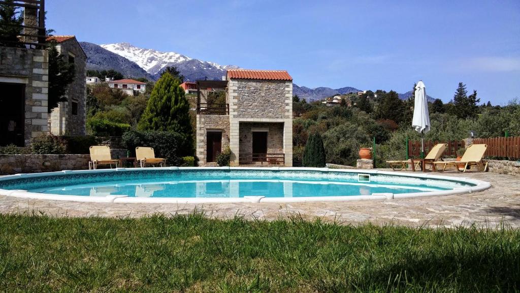 a swimming pool in a yard with mountains in the background at Stratos Villas in Melidhónion