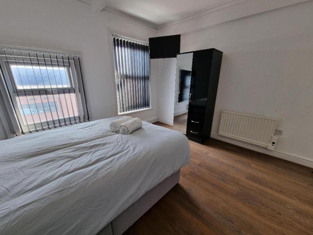 a bedroom with a large bed and two windows at PL Liverpool in Liverpool