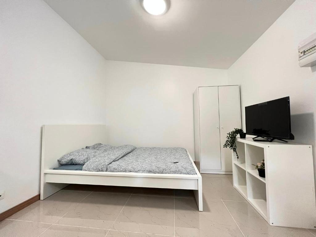 a white bedroom with a bed and a flat screen tv at Gagny Charmant studio 16m2 in Gagny