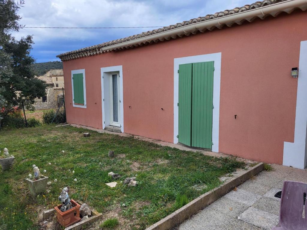 a house with green doors and a yard at Le MAS LES MARGAUDS in Malaucène