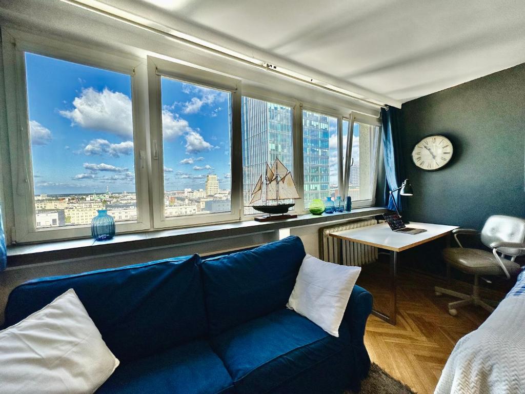 a living room with a blue couch in front of windows at Super Apartament WHITE Warszawa 2x Metro Ścisłe Centrum WiFi 300 Mbs NEW in Warsaw