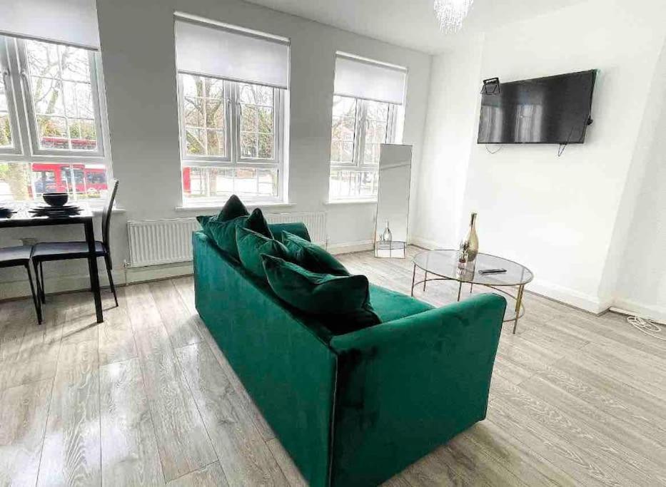 Immaculate 1 bedroom apartment in Orpington في أوربنغتون: غرفة معيشة مع أريكة خضراء وطاولة