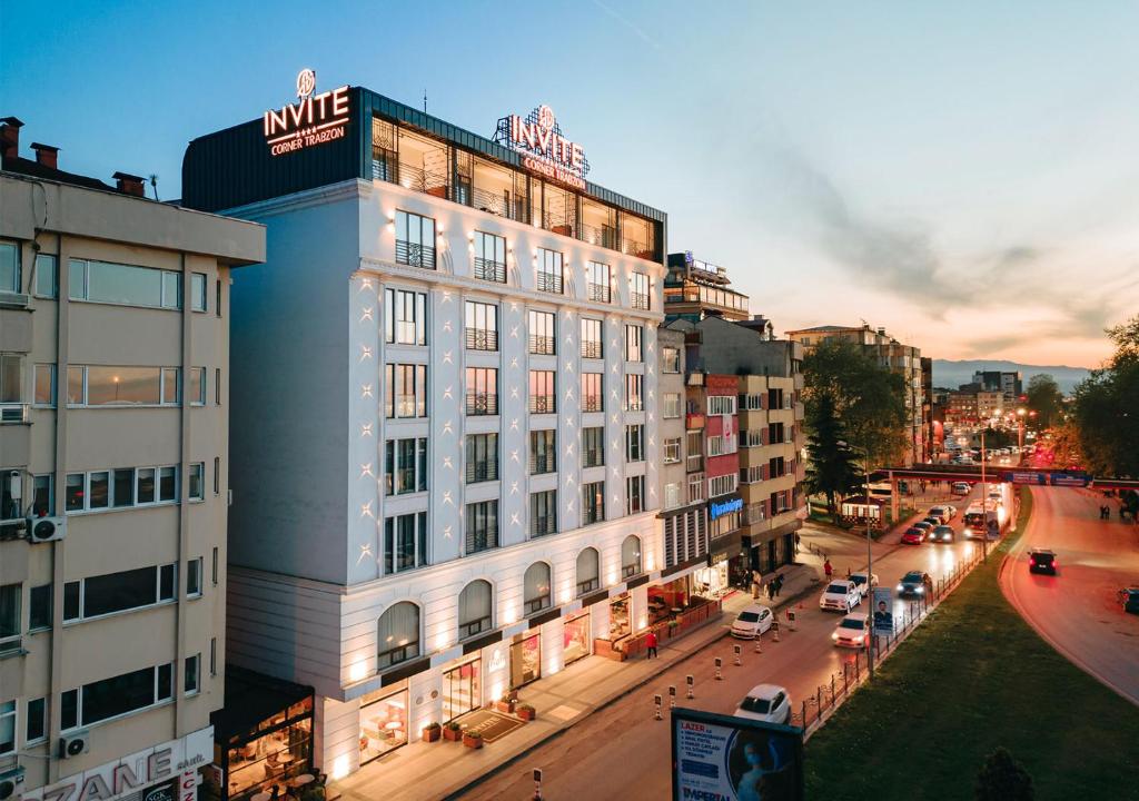 Invite Hotel Corner Trabzon في طرابزون: مبنى ابيض كبير على شارع المدينة وبه سيارات