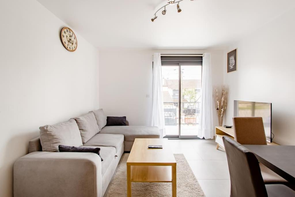 uma sala de estar com um sofá e uma mesa em Joli appartement proche Paris Orly em Morangis