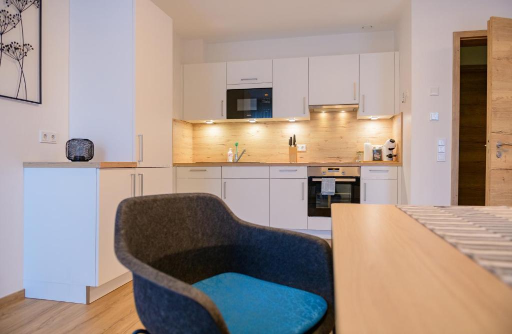 a kitchen with a table and a blue chair at Appart-Hotel Ernz Noire in Grundhof