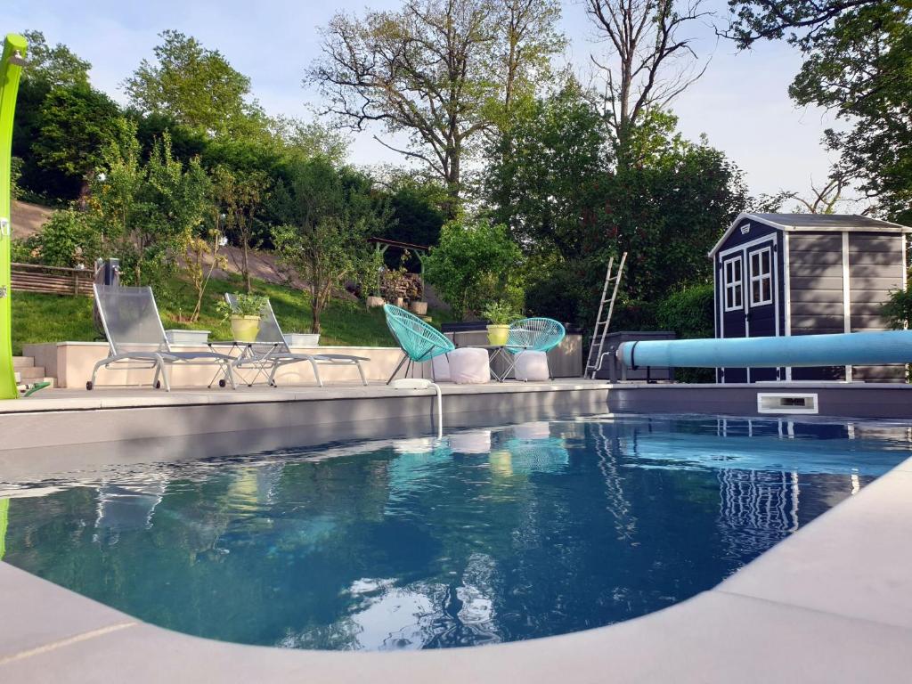a pool with chairs and a water slide at LE GÎTE DU CHEMIN ROUGE 
