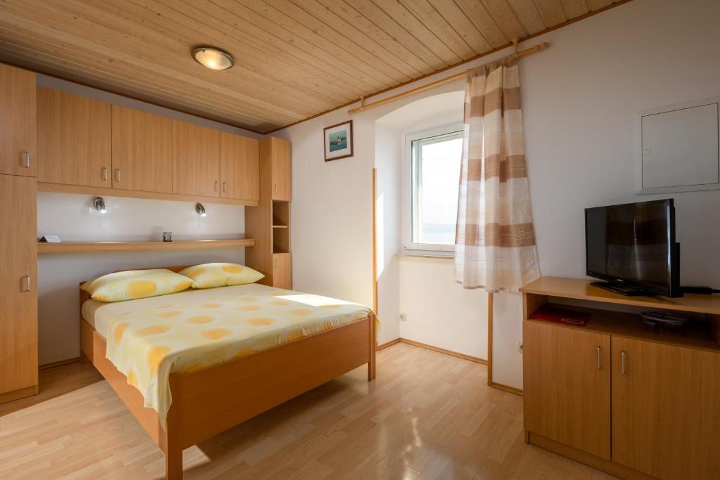- une petite chambre avec un lit et une télévision dans l'établissement Apartmani Matić, à Mošćenička Draga