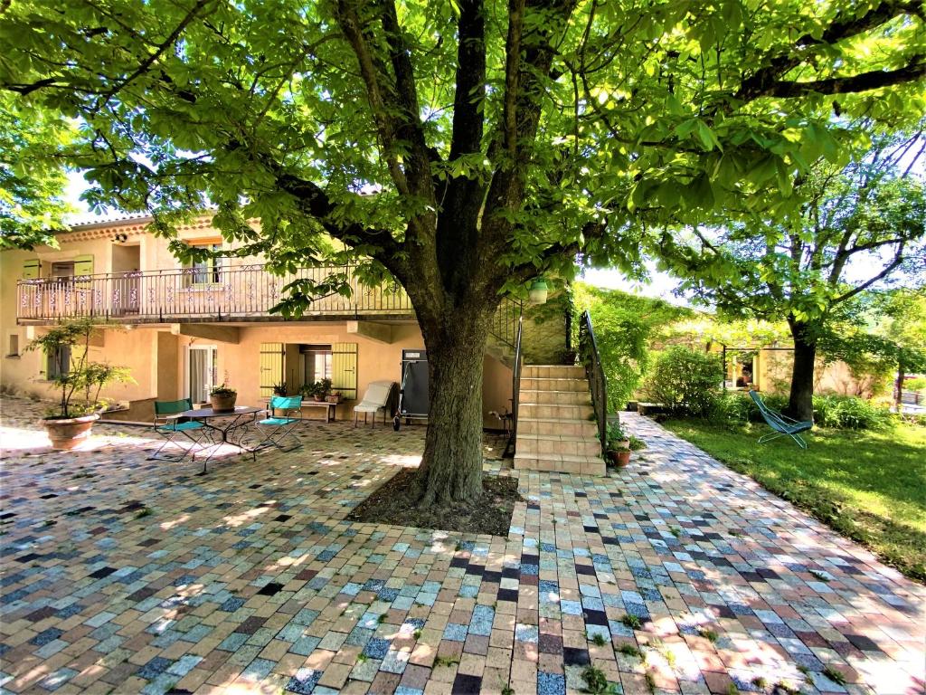a tree in the middle of a brick yard at CHAMBRES D&#39;HOTES 2 à 4p ou GITE DE GROUPE 15p, 7 ch, 6 sdb, parc et salle de réception in Villeneuve-de-Berg