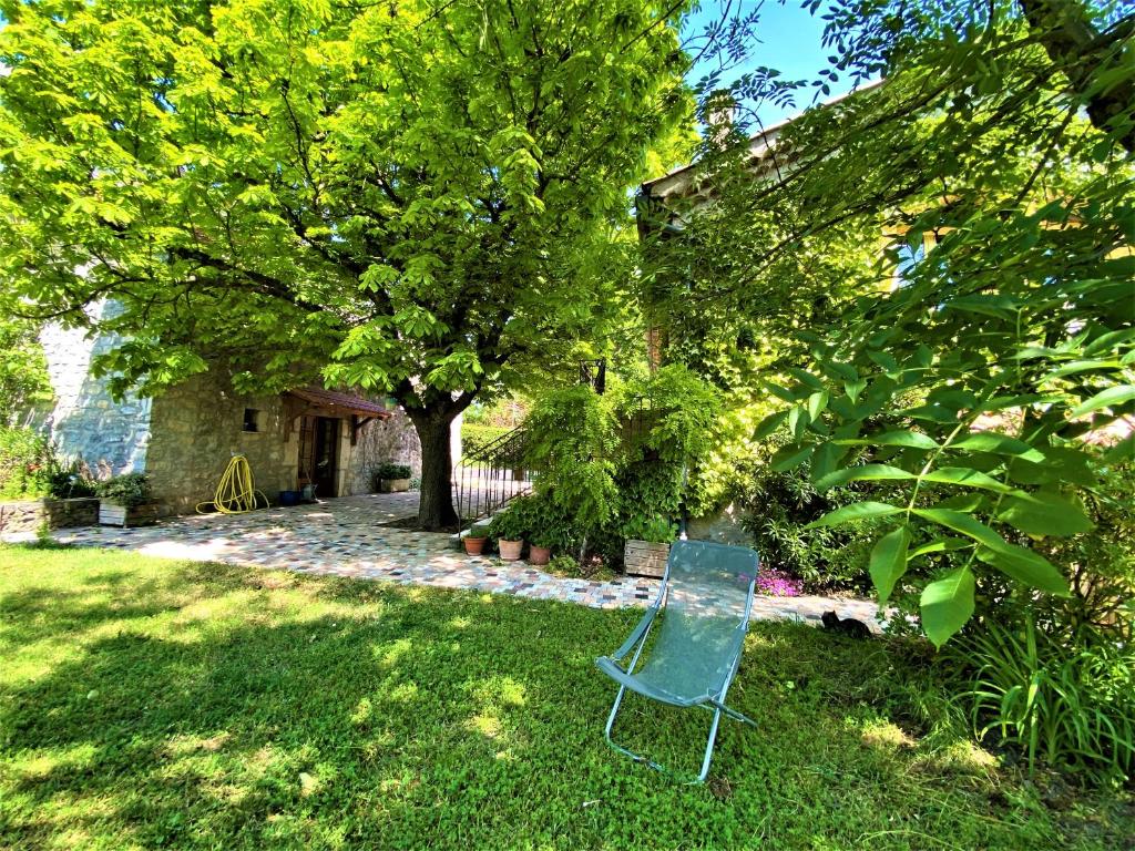 a green chair sitting in the grass in a yard at CHAMBRES D&#39;HOTES 2 à 4p ou GITE DE GROUPE 15p, 7 ch, 6 sdb, parc et salle de réception in Villeneuve-de-Berg