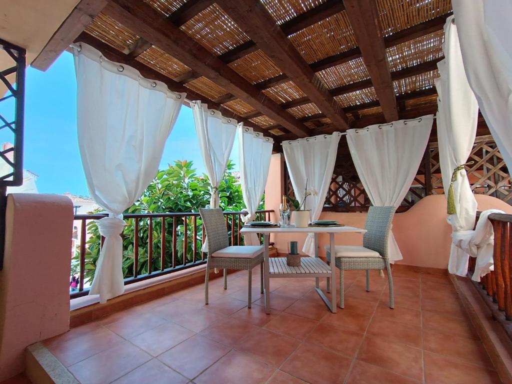 eine Terrasse mit einem Tisch und Stühlen auf dem Balkon in der Unterkunft La Maison Des Arches in Porto Cervo