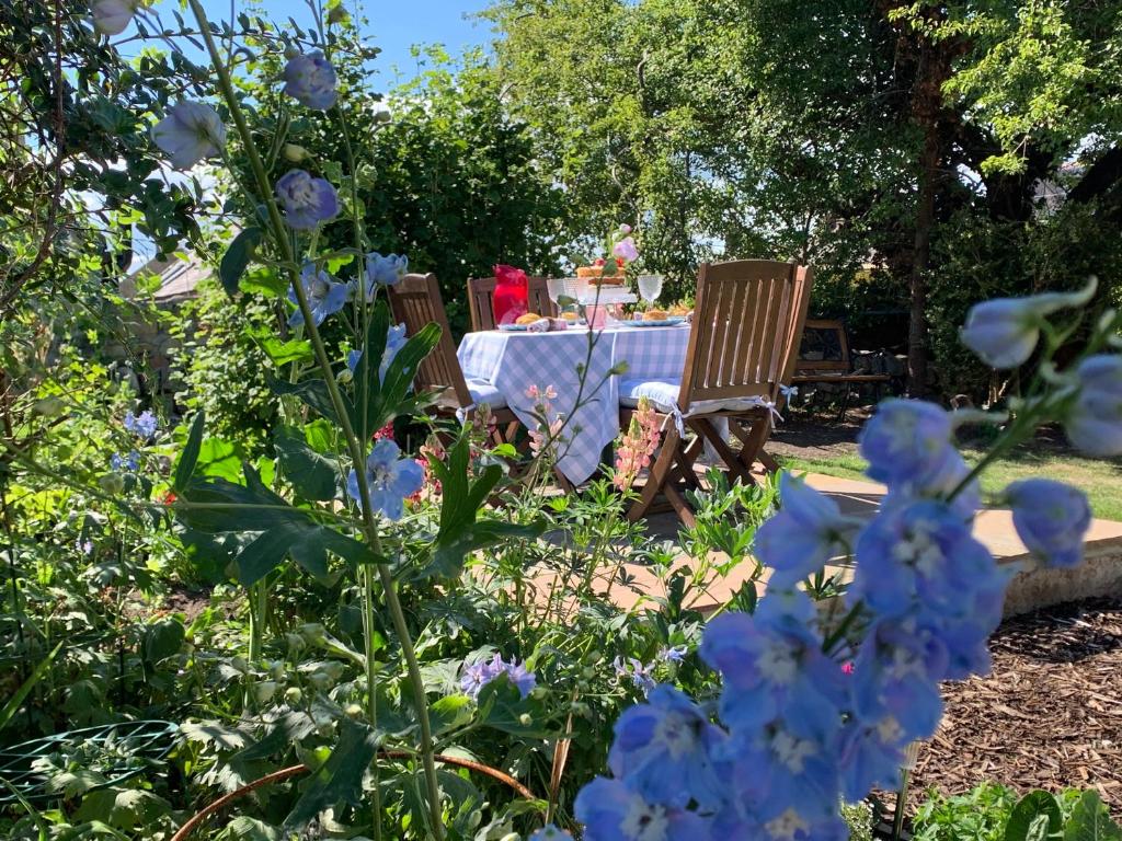 a garden with a table and chairs and blue flowers at Atte Combe Cottage in Acomb