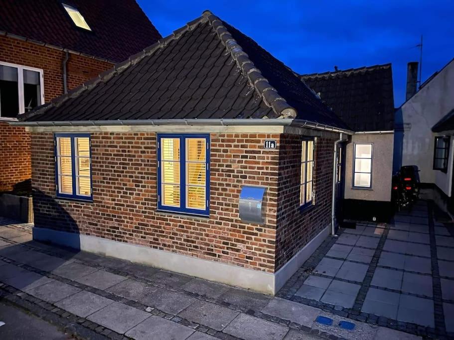 a brick house with blue and yellow shutters at Hyggeligt lille byhus lige mellem havnen og bytorv in Ringkøbing