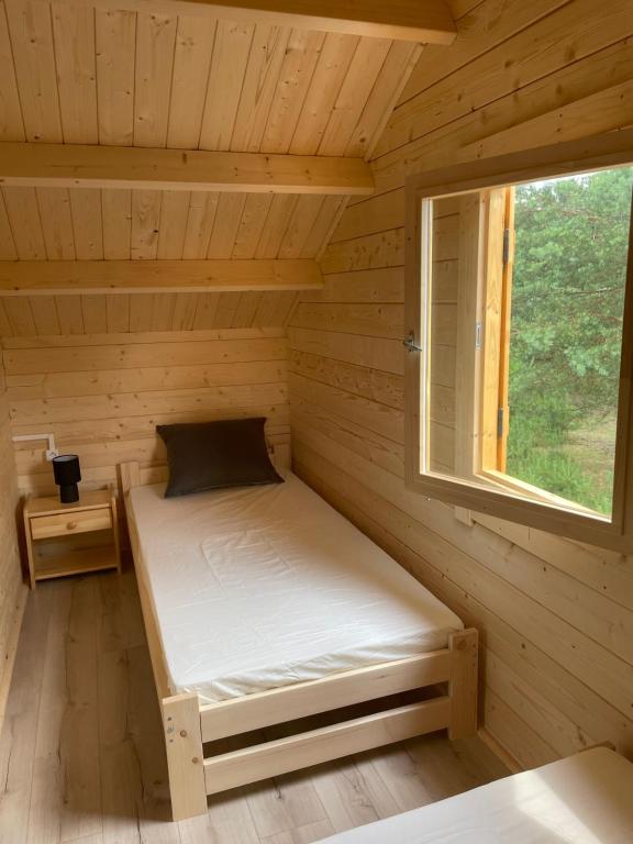 małe łóżko w drewnianym pokoju z oknem w obiekcie Osada Gardenia w Ślesinie