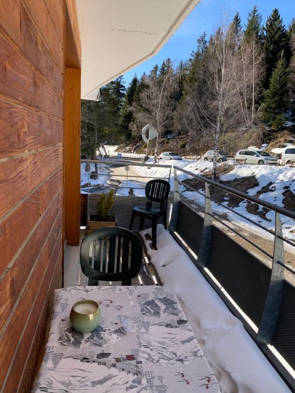 einen Balkon mit einem Tisch und Stühlen sowie Schnee auf dem Boden in der Unterkunft Appartement Chamrousse in Chamrousse
