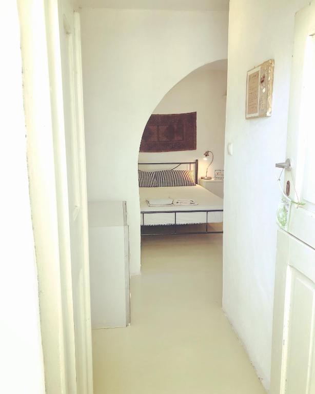 a white room with a bed and a refrigerator at Sunset House in Serifos Chora