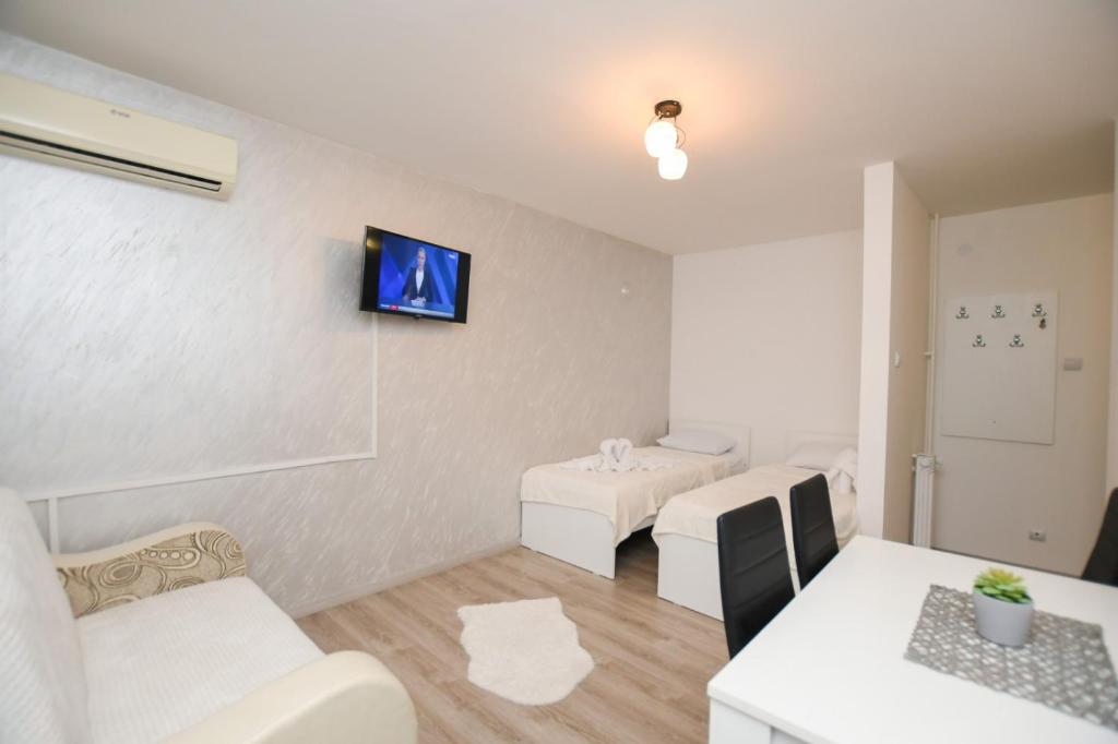 un soggiorno con mobili bianchi e TV a parete di Apartman Jana a Kladovo