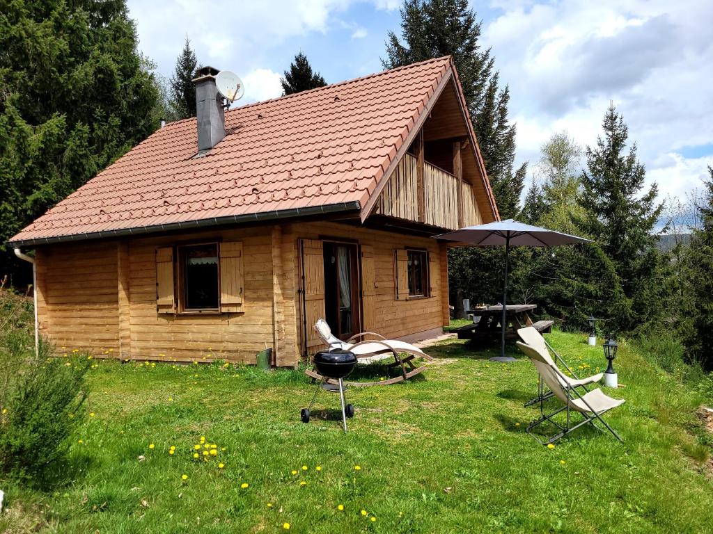 ein kleines Holzhaus mit zwei Stühlen und einem Sonnenschirm in der Unterkunft Chalet de la Grimpette au coeur de Gérardmer in Gérardmer