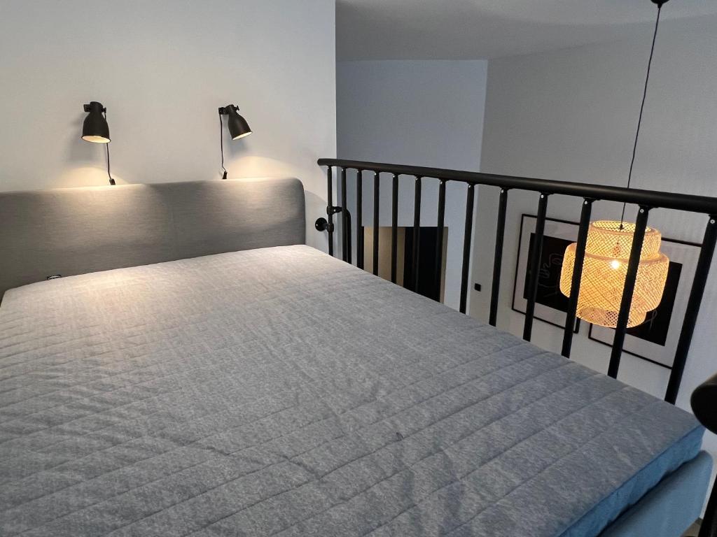 Bett in einem Zimmer mit zwei Leuchten in der Unterkunft I&M Apartments Rejtana Wrocław in Breslau