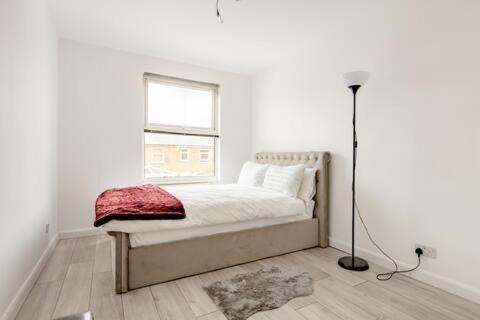 Lovely and comfortable Home Stay in London في لندن: غرفة نوم بيضاء بها سرير ونافذة