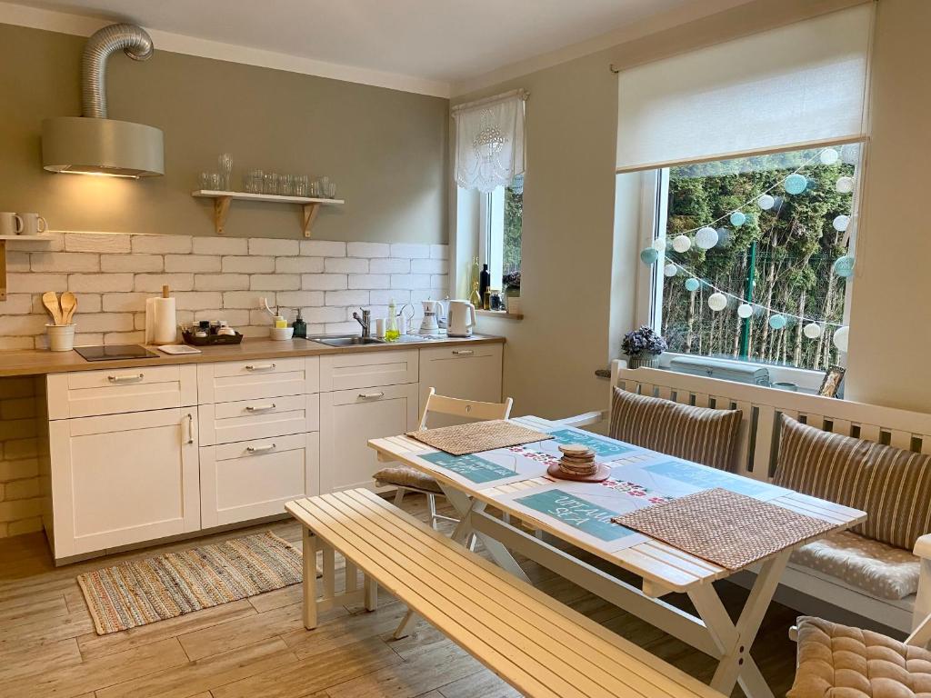 a kitchen with a table and a dining room at Szary Domek Apartamenty Ustka in Ustka