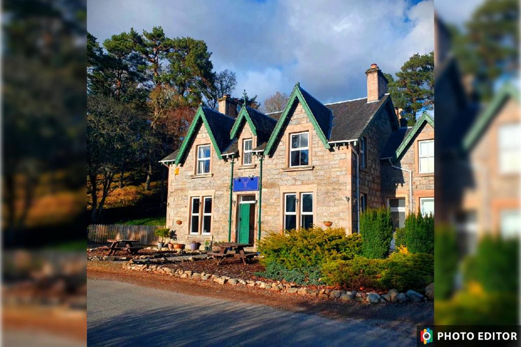 uma grande casa de pedra com uma porta verde em Strathardle Lodge em Kirkmichael