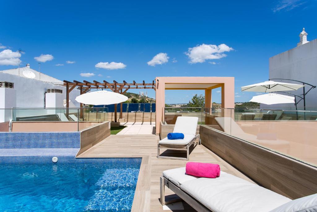 uma piscina com duas espreguiçadeiras e uma piscina em Casa Amarela Guesthouse em Albufeira