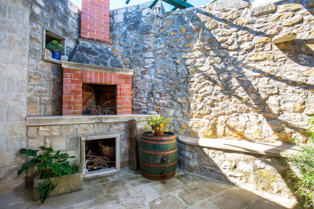 a stone wall with a barrel and a fireplace at Visilo Stone House in Pučišća