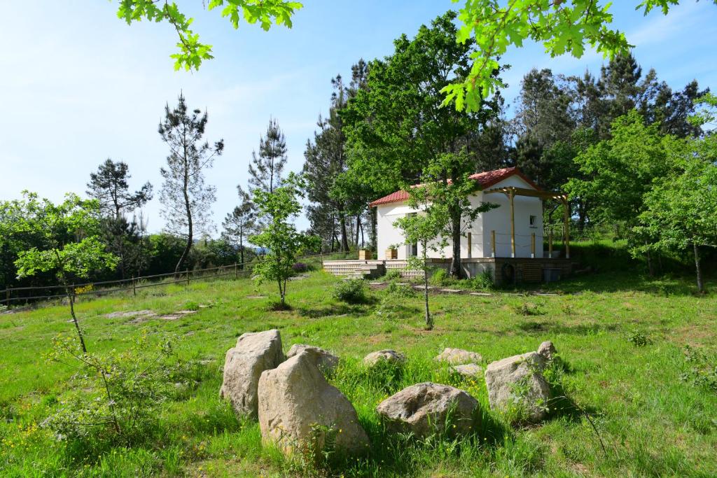 una pequeña casa blanca en un campo con rocas en Casinha Rubiães en Paredes de Coura