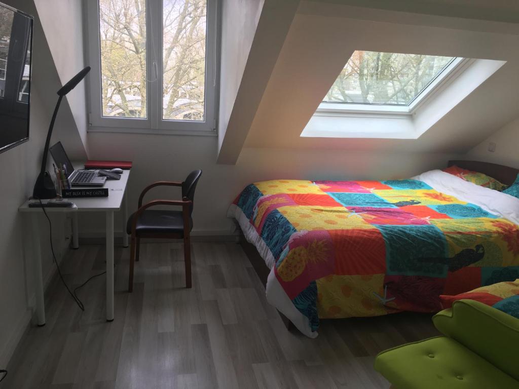 1 dormitorio con 1 cama, escritorio y 2 ventanas en Agréable chambre indépendante chez Virginie&Henri, en Le Mée-sur-Seine