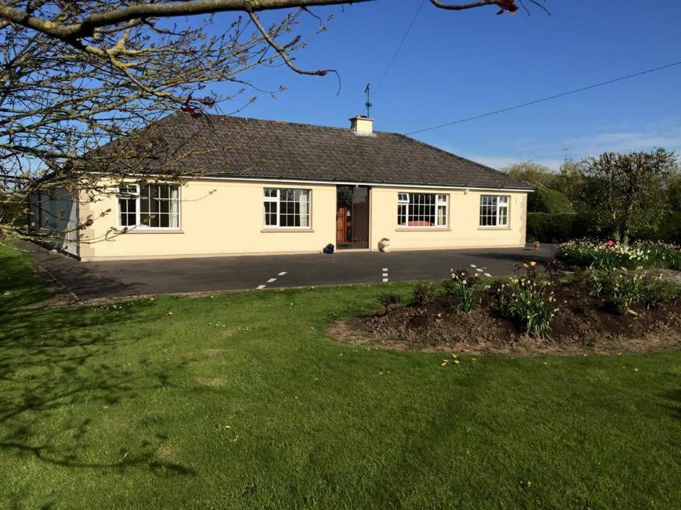 een wit huis met een oprit en een tuin bij Hawthorn View Bed and Breakfast in Thurles