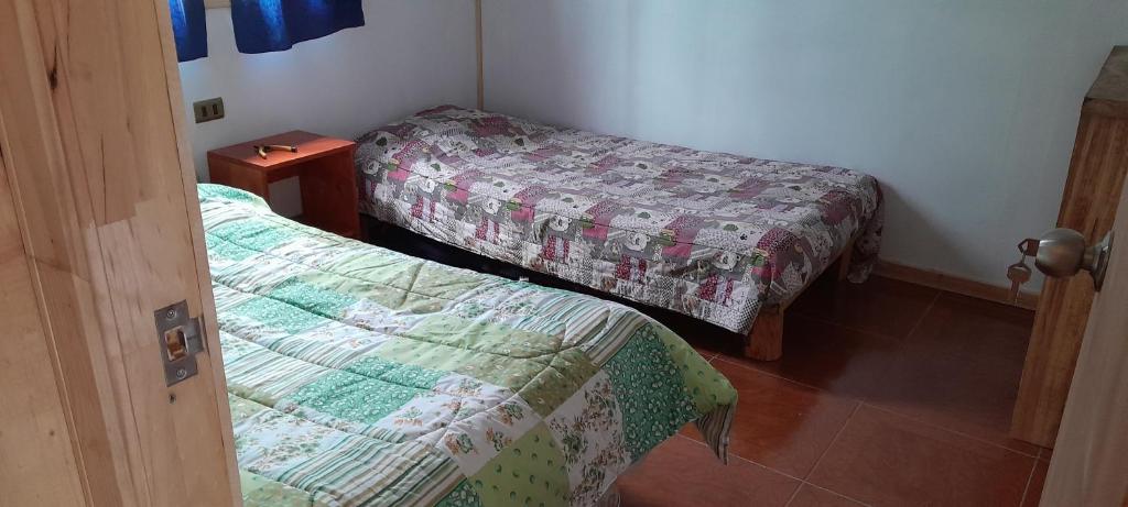 a bedroom with two beds and a night stand with a bedskirts at Cabañas,Buena vista. in Coñaripe