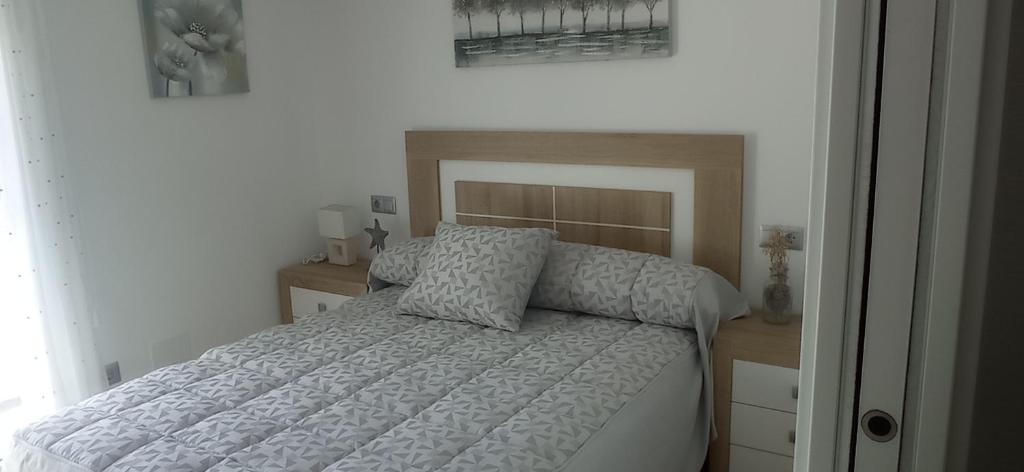 1 dormitorio con cama blanca y cabecero de madera en Casa Ageitos, en Vimianzo