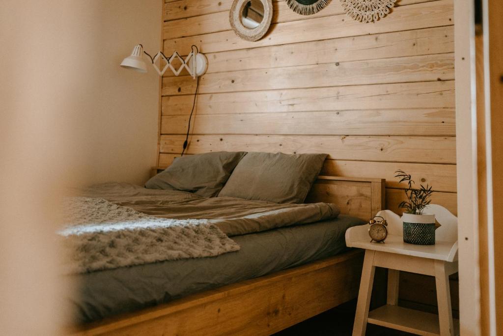 a bed in a room with a wooden wall at Na miły Bug Guesthouse by Bug river 