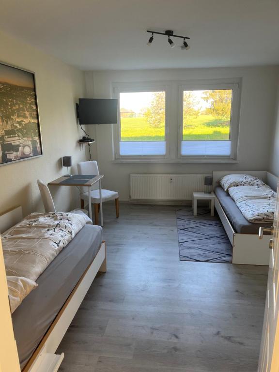1 Schlafzimmer mit 2 Betten, einem Schreibtisch und 2 Fenstern in der Unterkunft Monteur-Pension N2 