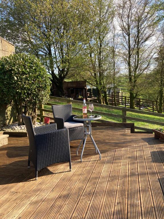 a patio with two chairs and a table with a bottle of wine at Weather Hill Cottage, Hebden Bridge in Hebden Bridge