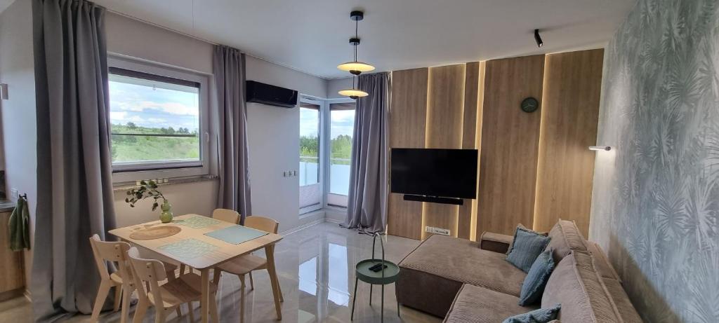 - un salon avec un canapé et une table dans l'établissement 62m2 Apartament PREMIUM Łąki i Pola, ELEKTRYCZNE ROLETY, KLIMATYZACJA, GARAŻ, ŁADOWARKA AUT ELEKTRYCZNYCH, à Suwałki