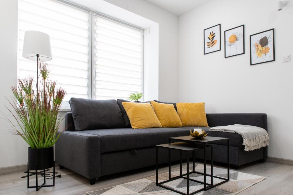 a living room with a black couch with yellow pillows at The Central Border Premium Apartment in Štúrovo