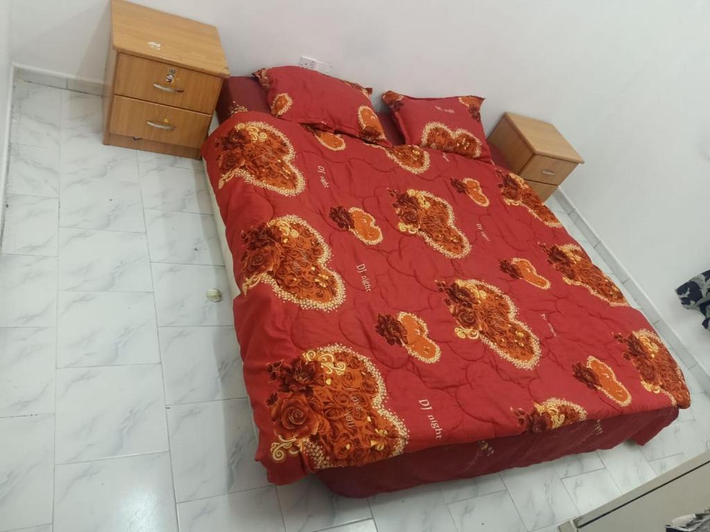 Una cama con un edredón rojo con flores. en Private room for upto 4 peope, en Sharjah