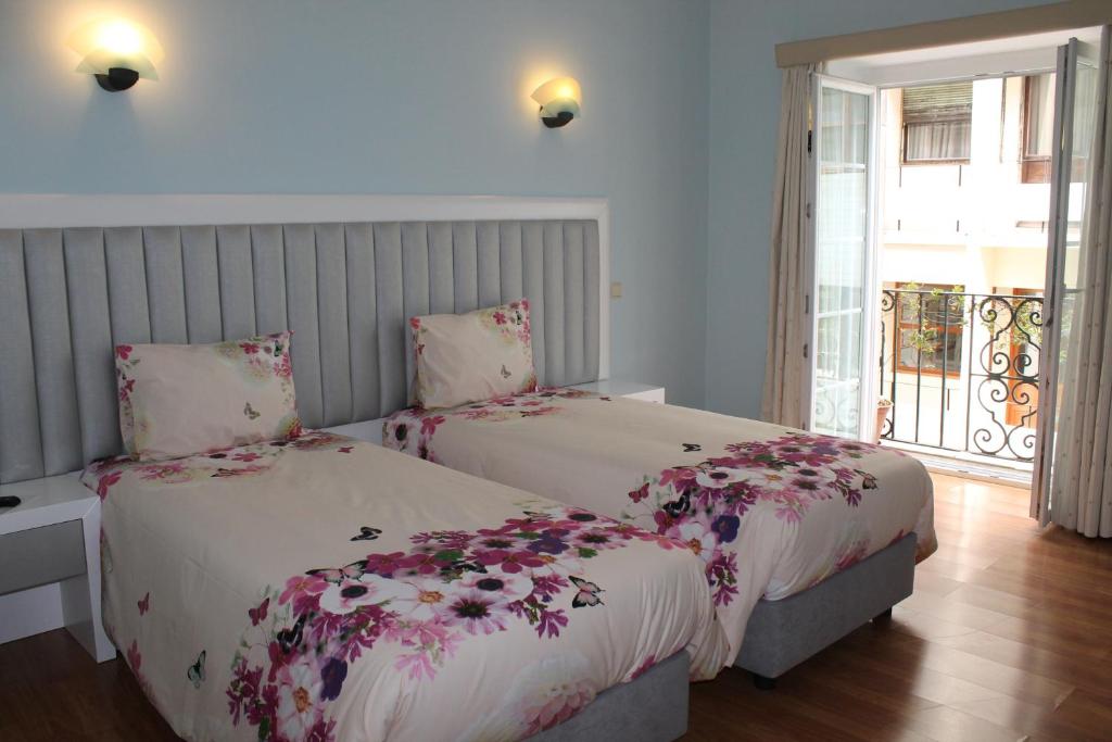 Grande Oceano Guest House في بورتو: غرفة نوم بسريرين وعليها ورد
