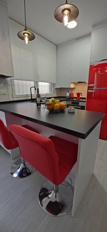 a kitchen with a black counter and red bar stools at Loft A la verita River,PARKING PRIVADO GRATIS in Córdoba